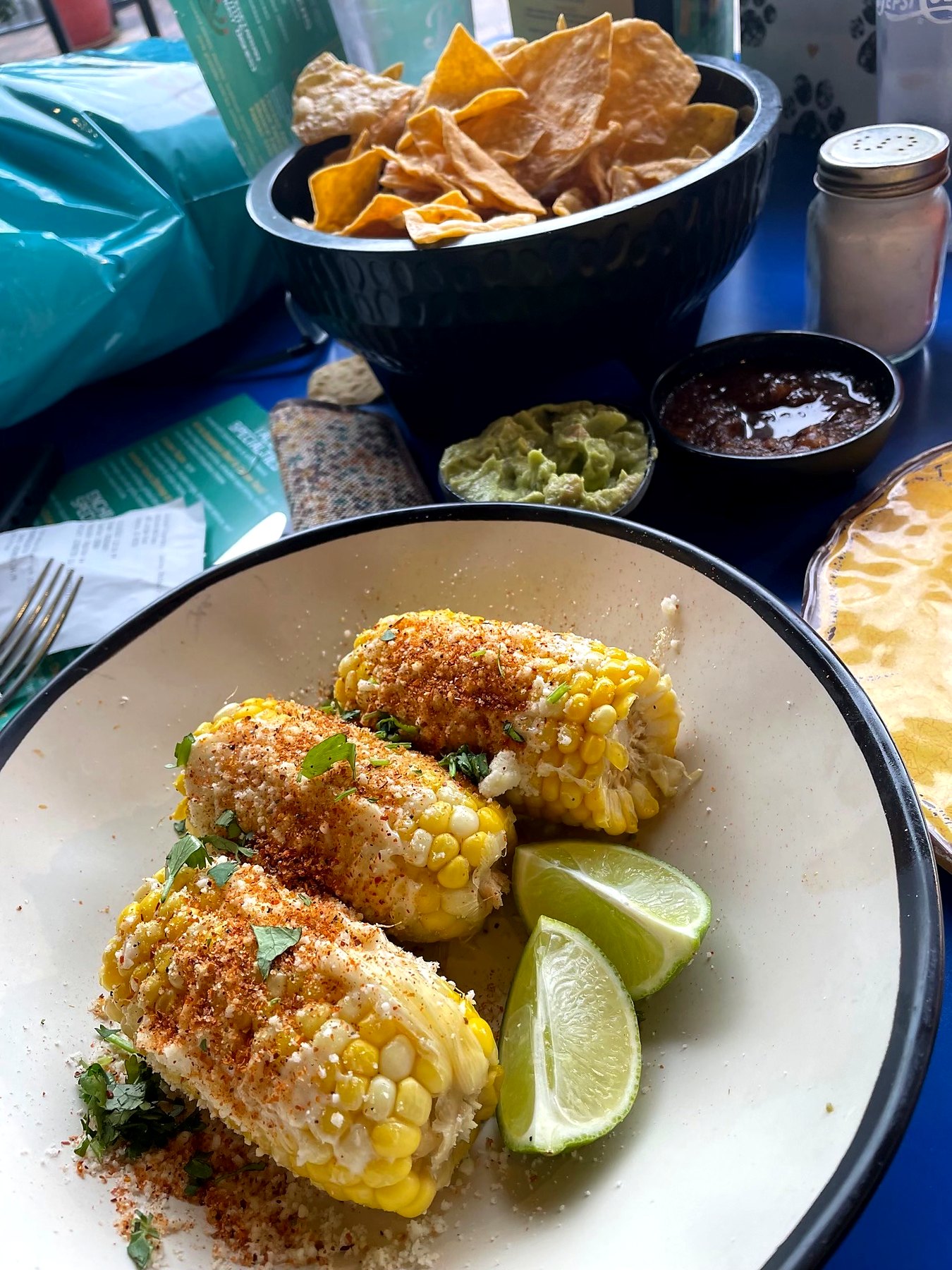 Seasoned corn on the cob topped with herbs and served with lime wedges.