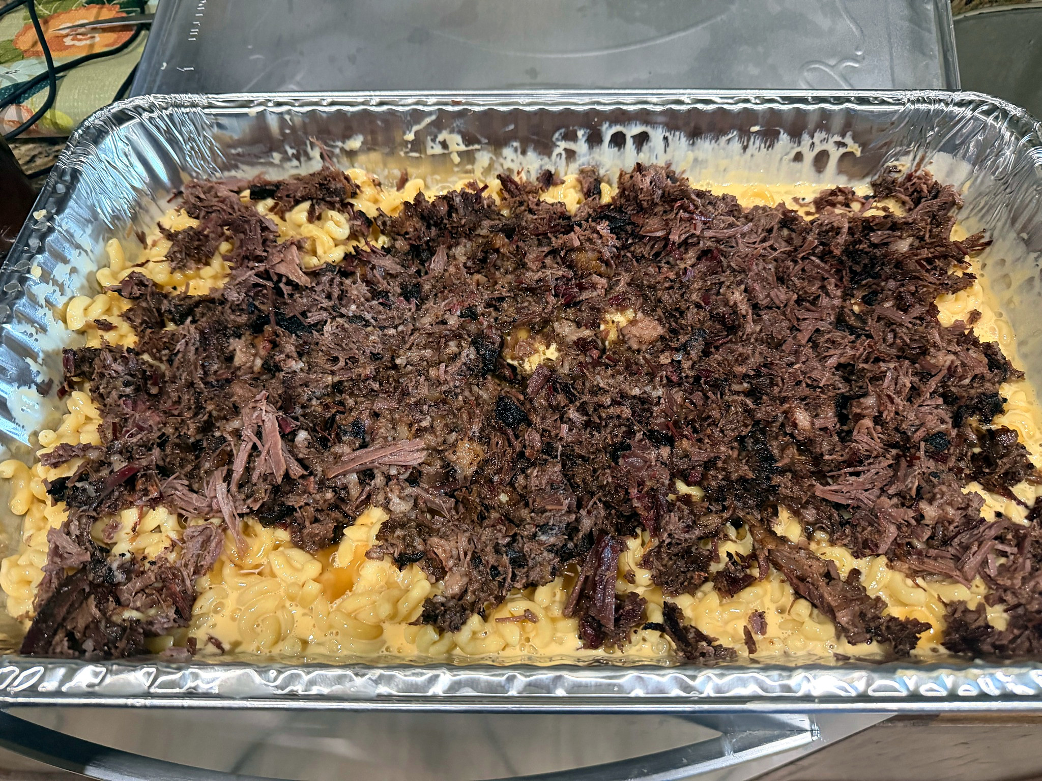 Tray of creamy mac and cheese topped with smoked brisket.