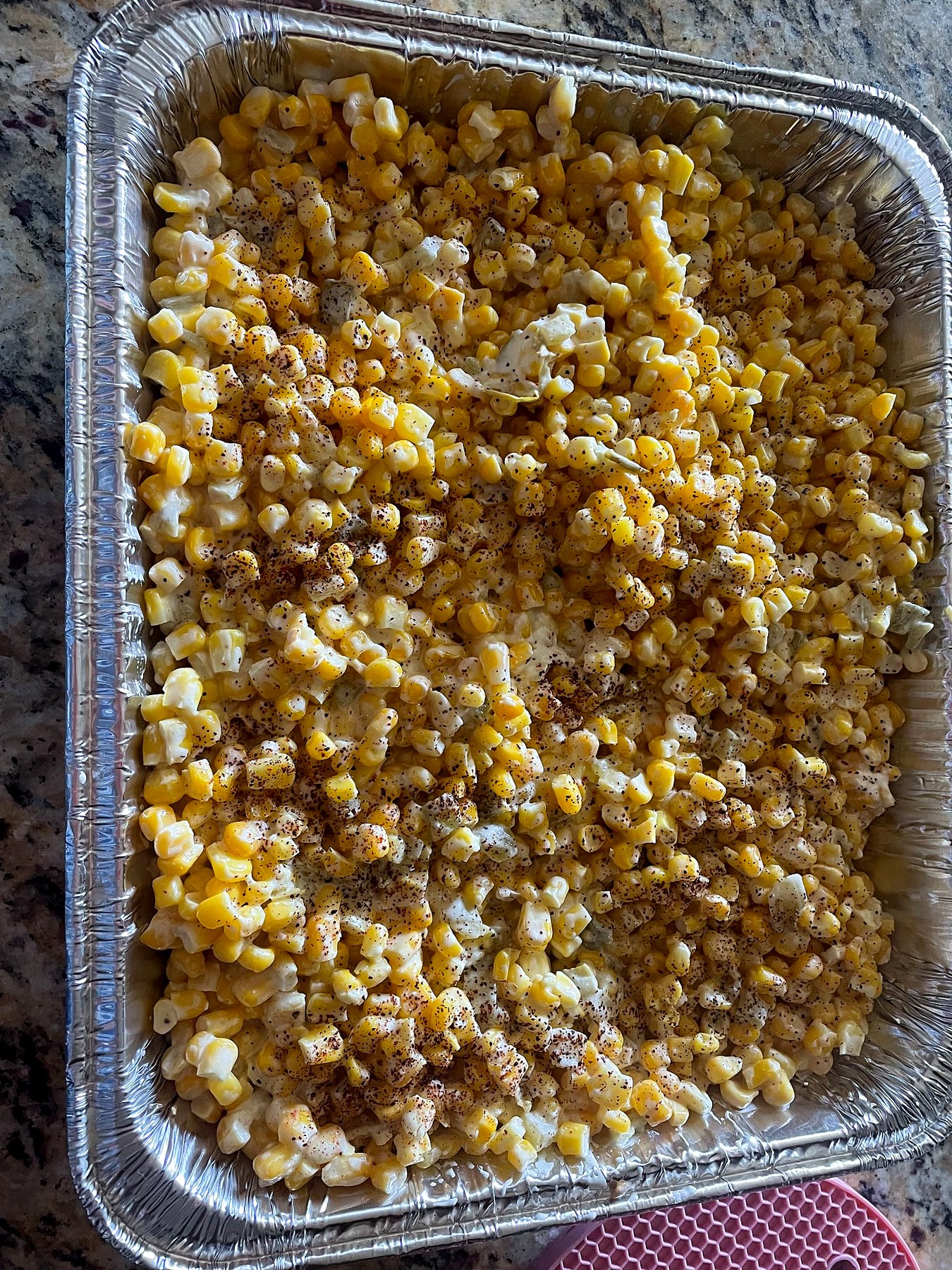 A catering tray filled with green chili corn.
