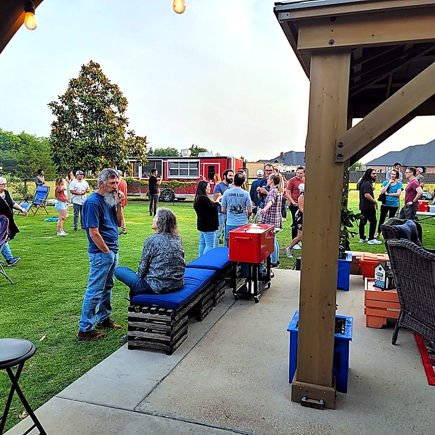 An outdoor event with guests gathered near the Red Cooler BBQ trailer.